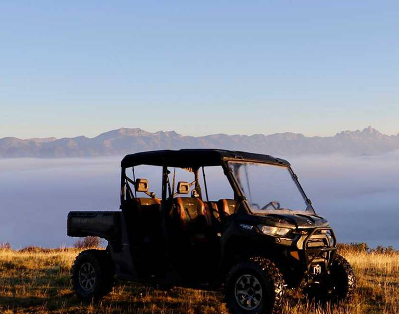 A black ATV parked in front of a foggy mountain range.